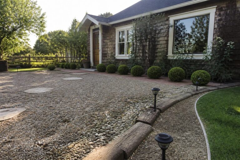 17 Easy DIY Driveway Ideas for a Simple Weekend Upgrade Gravel path with stepping stones to white house porch lined with bushes and lights.