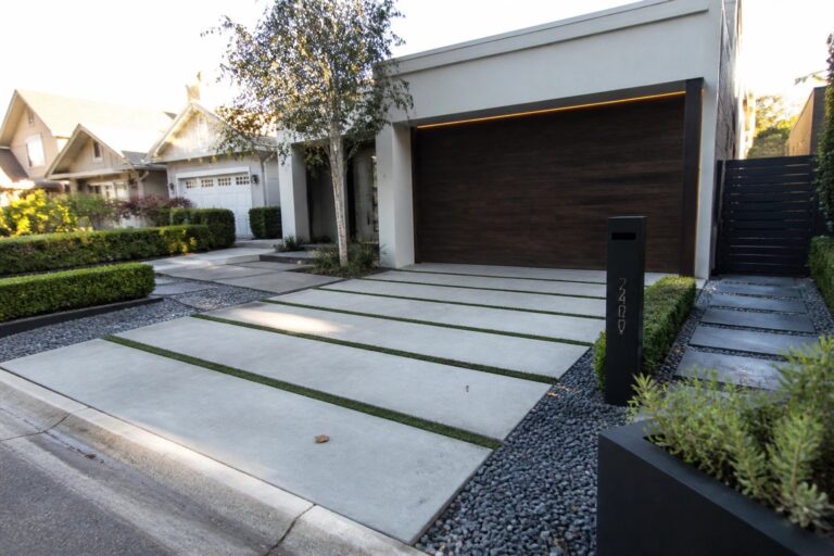 Modern house with dark wood garage door, concrete driveway with grass strips.