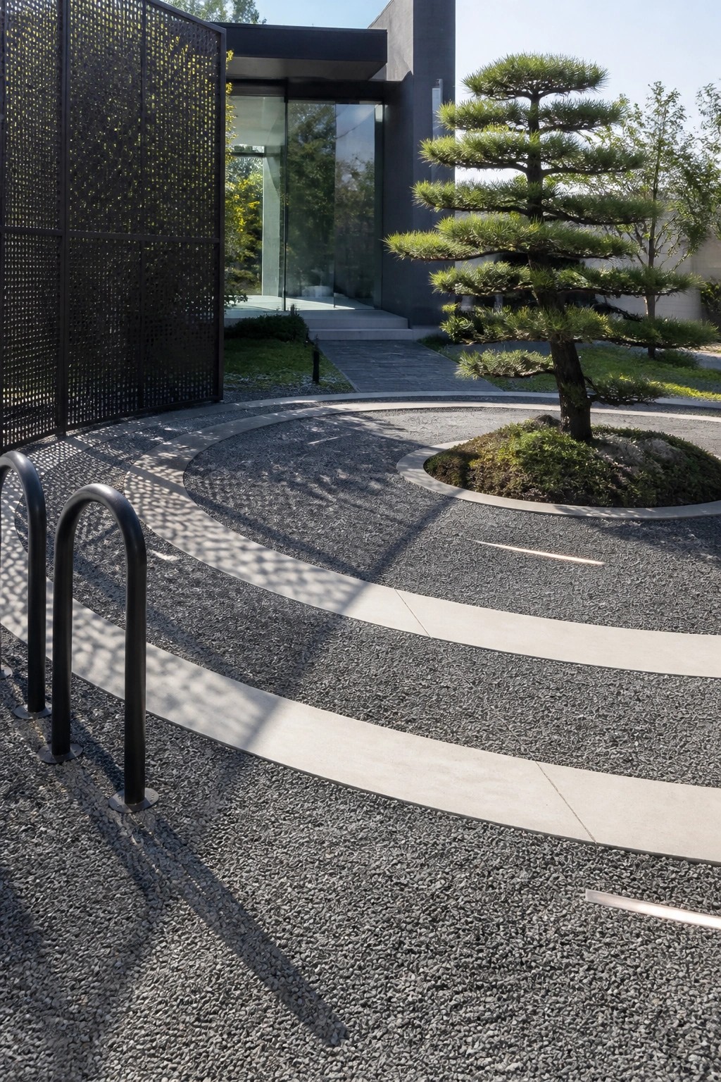 Modern gravel courtyard with curved concrete paths, pine tree, and black metal screen