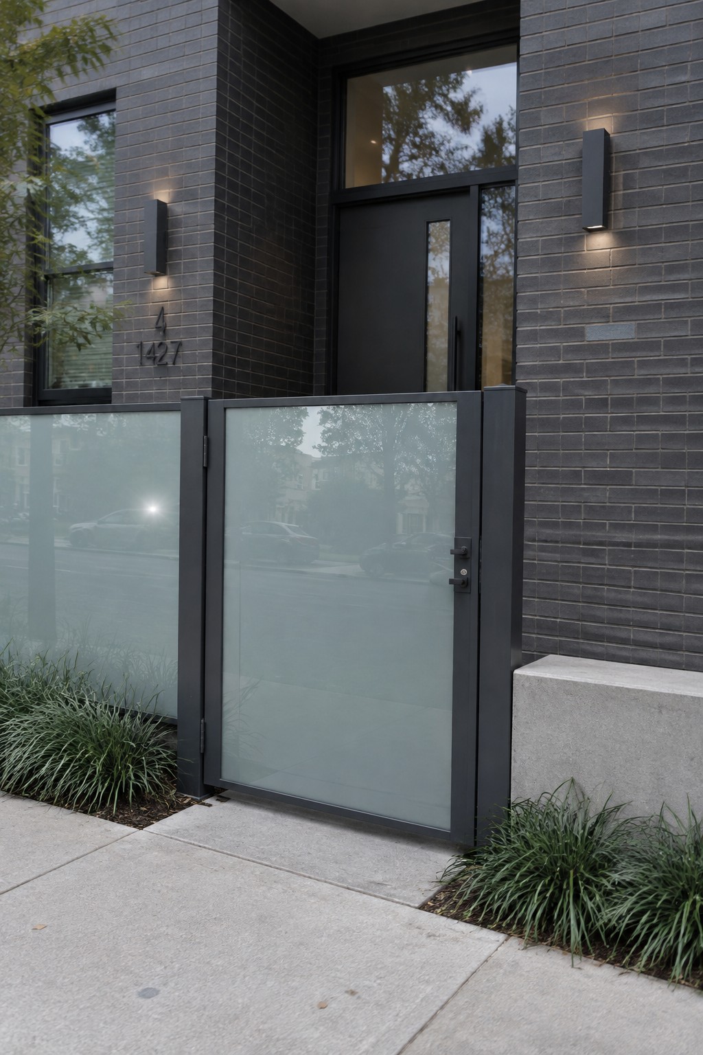 Modern building entrance with dark bricks, black door, frosted glass gate and lights