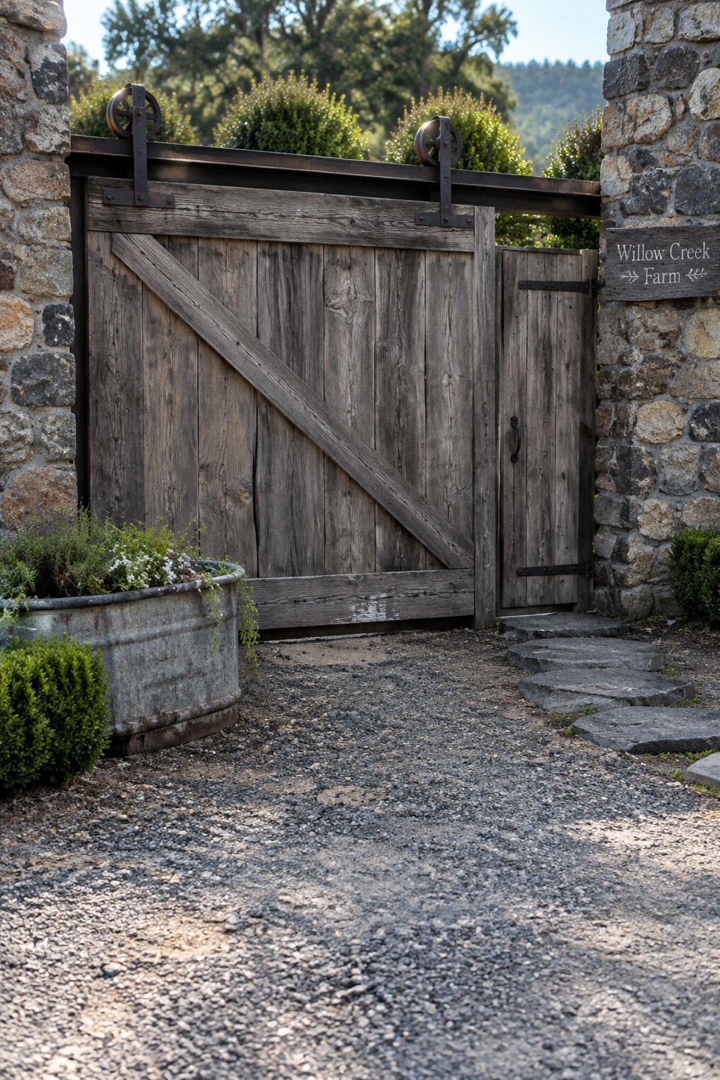 Rustic wooden sliding gate between stone pillars at Willow Creek Farm with gravel path