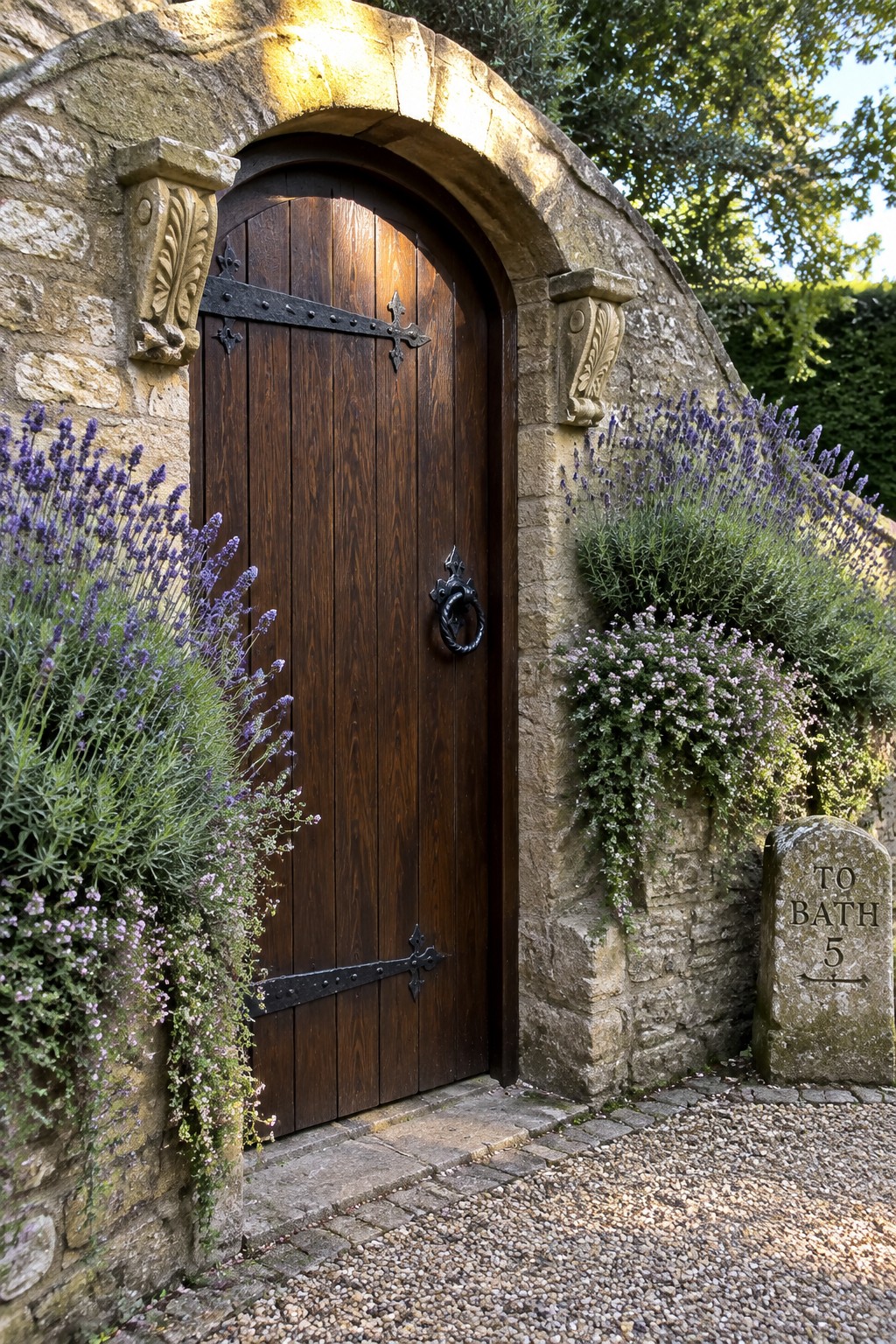 Rustic wooden door in stone archway beside lavender bushes and milestone sign